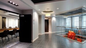 A modern hotel lobby with a reception desk, seating area, and a glass-enclosed atrium with a decorative orange sculpture. - Courtyard by Marriott Atlanta Downtown (Atlanta)