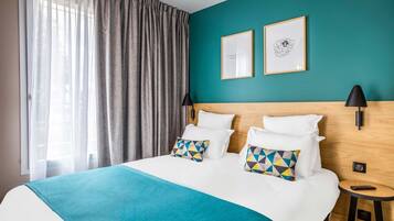 Une chambre d’hôtel avec un grand lit, deux oreillers, un mur de couleur turquoise et un tableau encadré.