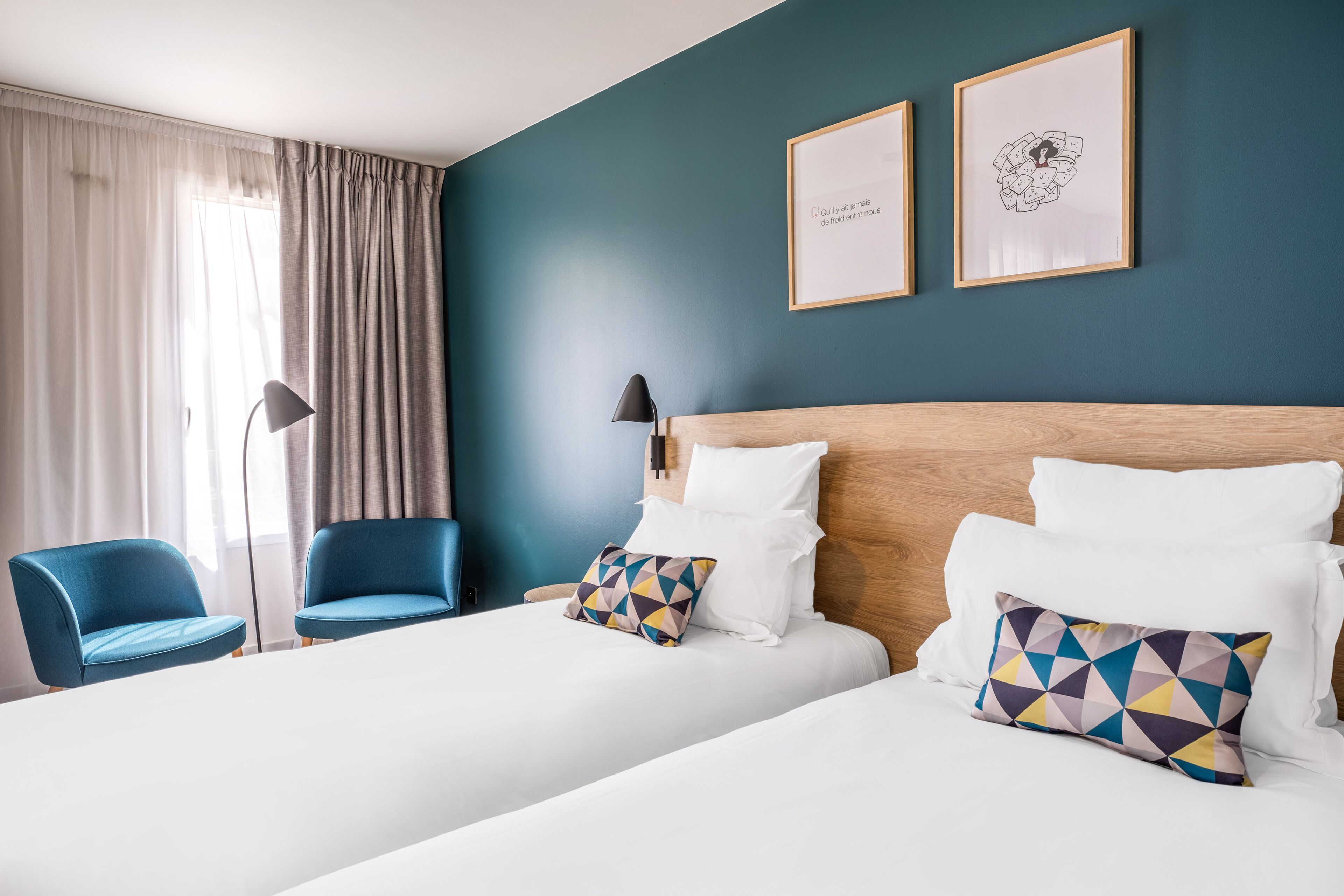 Een hotelkamer met een groot bed, twee stoelen, een bureau en een lamp.