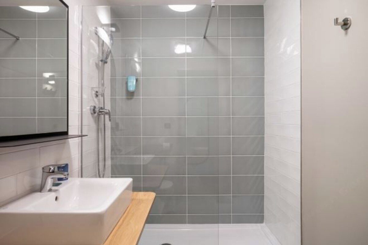 A bathroom with a shower, a sink, and a mirror.