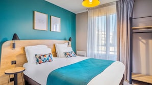 A modern hotel room with a large bed, a bedside table, a lamp, and a window with curtains. - Appart'City Confort St Quentin en Yvelines - Bois d'Arcy (Bois-d'Arcy)