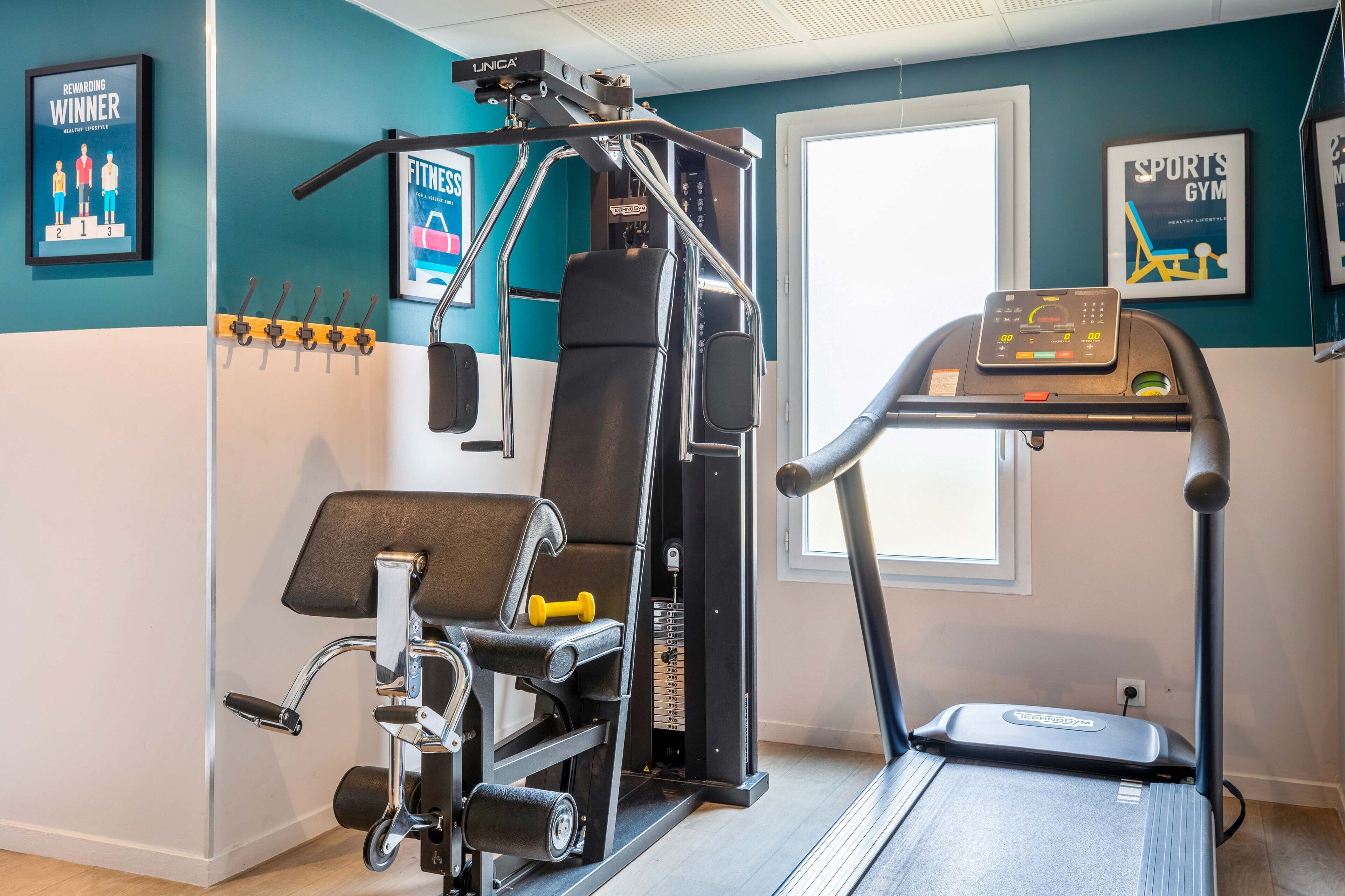 A gym with a treadmill, weight machine, and dumbbells.