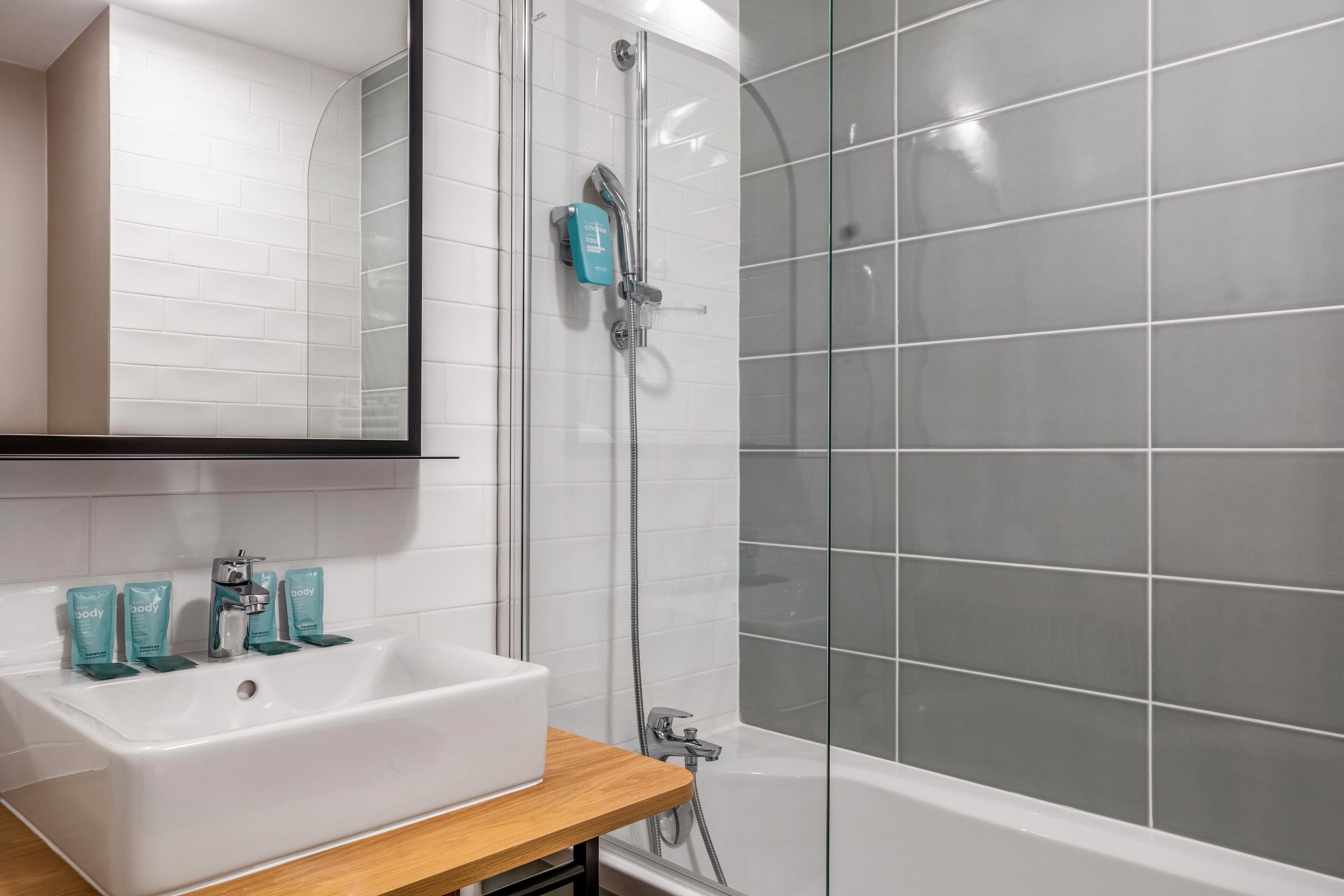 A bathroom with a white sink, a mirror, and a shower area with a glass door.