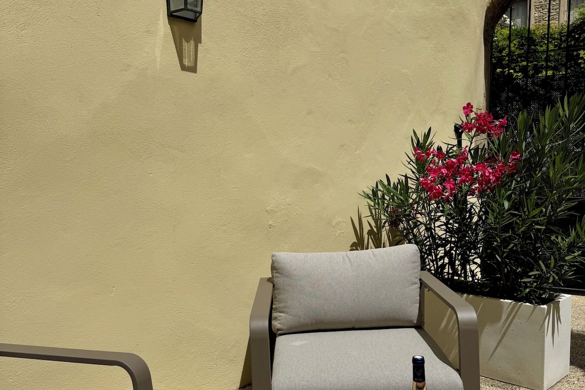 An outdoor seating area with a table, two chairs, a bottle, and a box of biscuits.