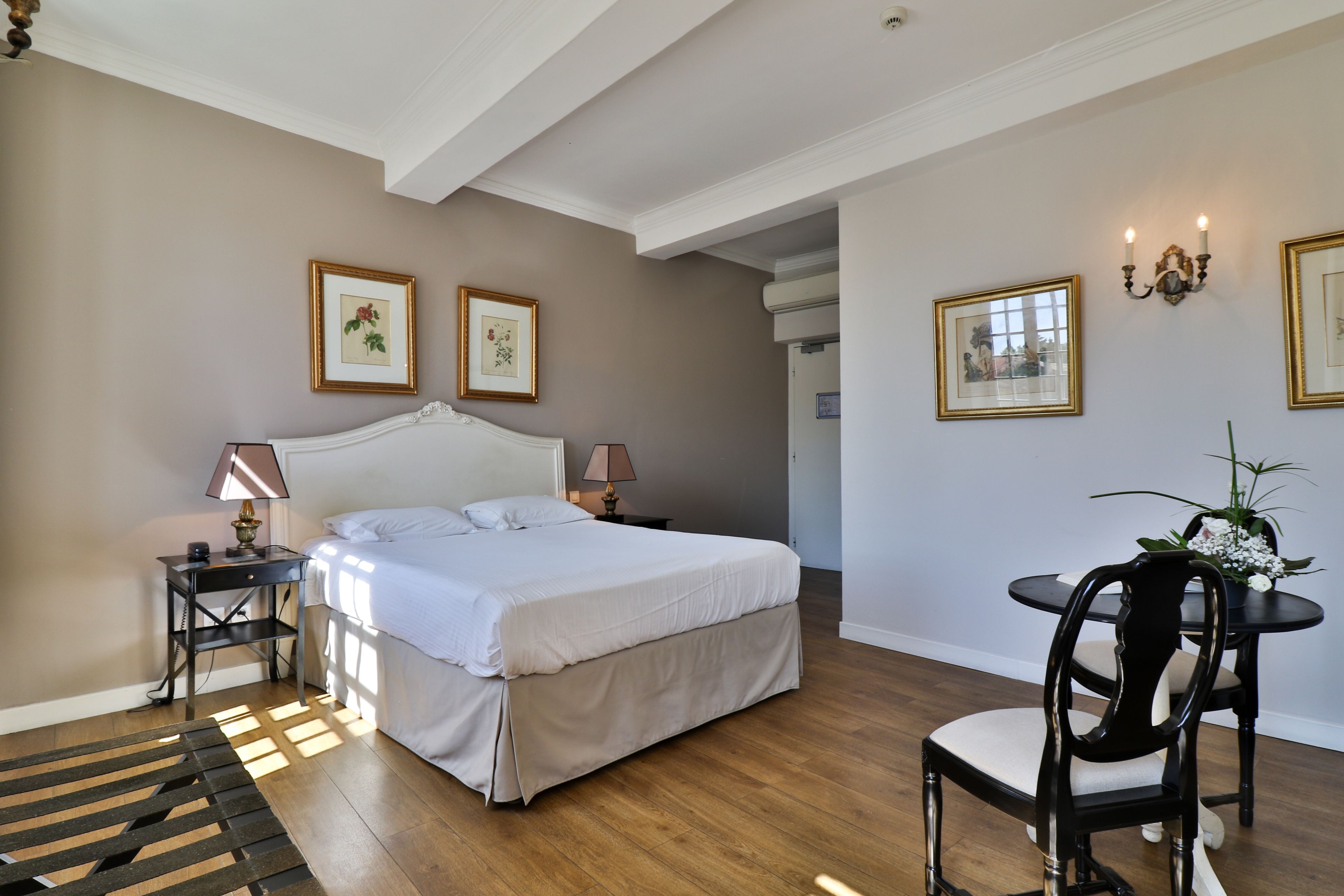 A bedroom with a large bed, bedside tables, a chair, and framed pictures on the walls.