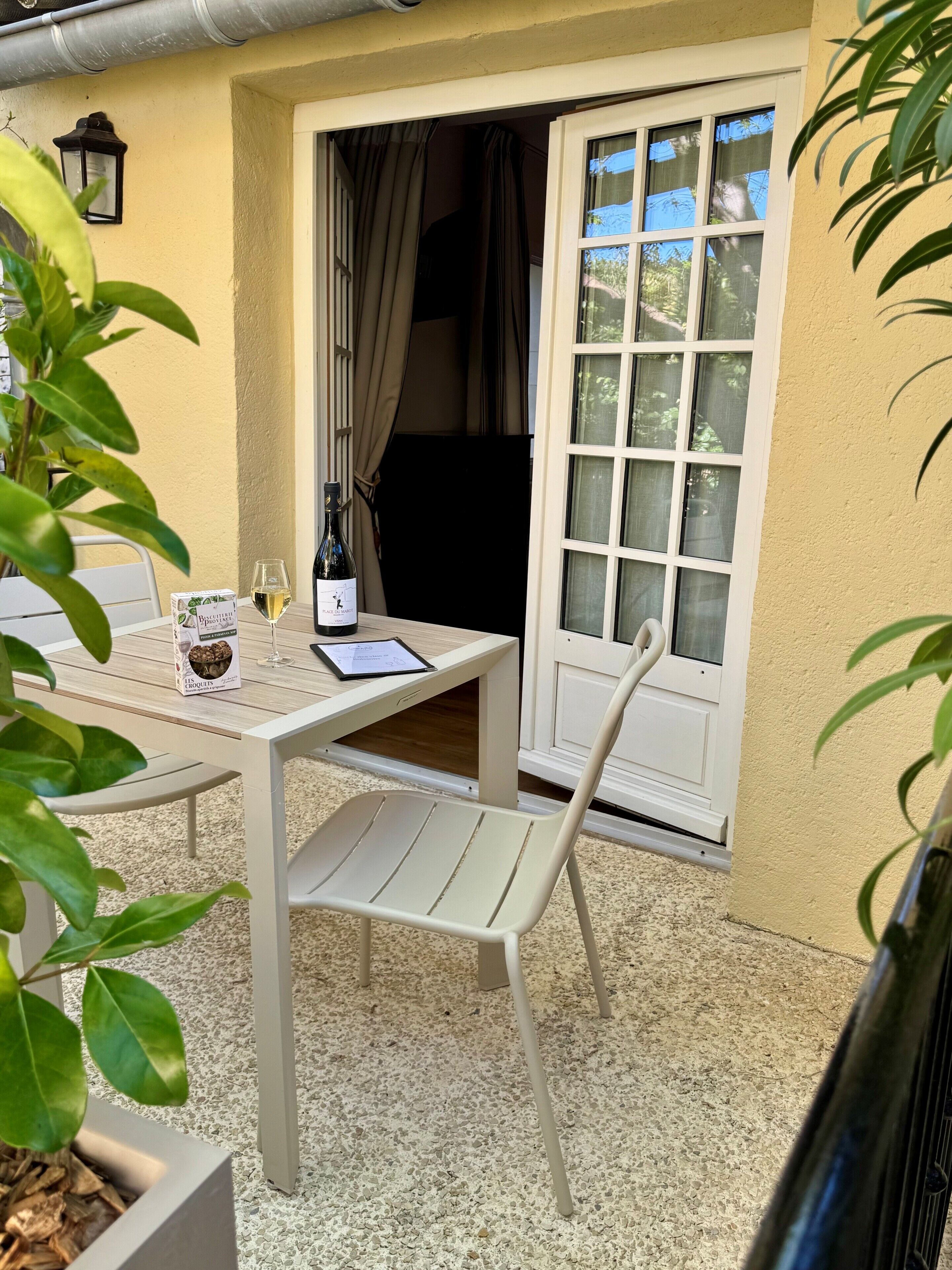 Un patio con una mesa, sillas, una botella de vino, una copa y un menú.