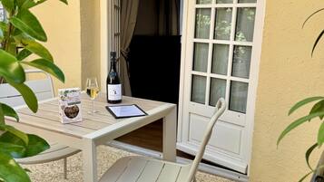Un patio con una mesa, sillas, una botella de vino, una copa y un menú.