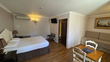 Een hotelkamer met een groot bed, een bureau, een stoel, een bank, een televisie en een schilderij aan de muur.