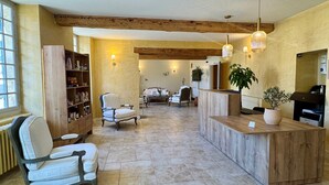 A spacious lobby with a reception desk, seating area, and a bookshelf. - Hôtel du Midi (Visan)