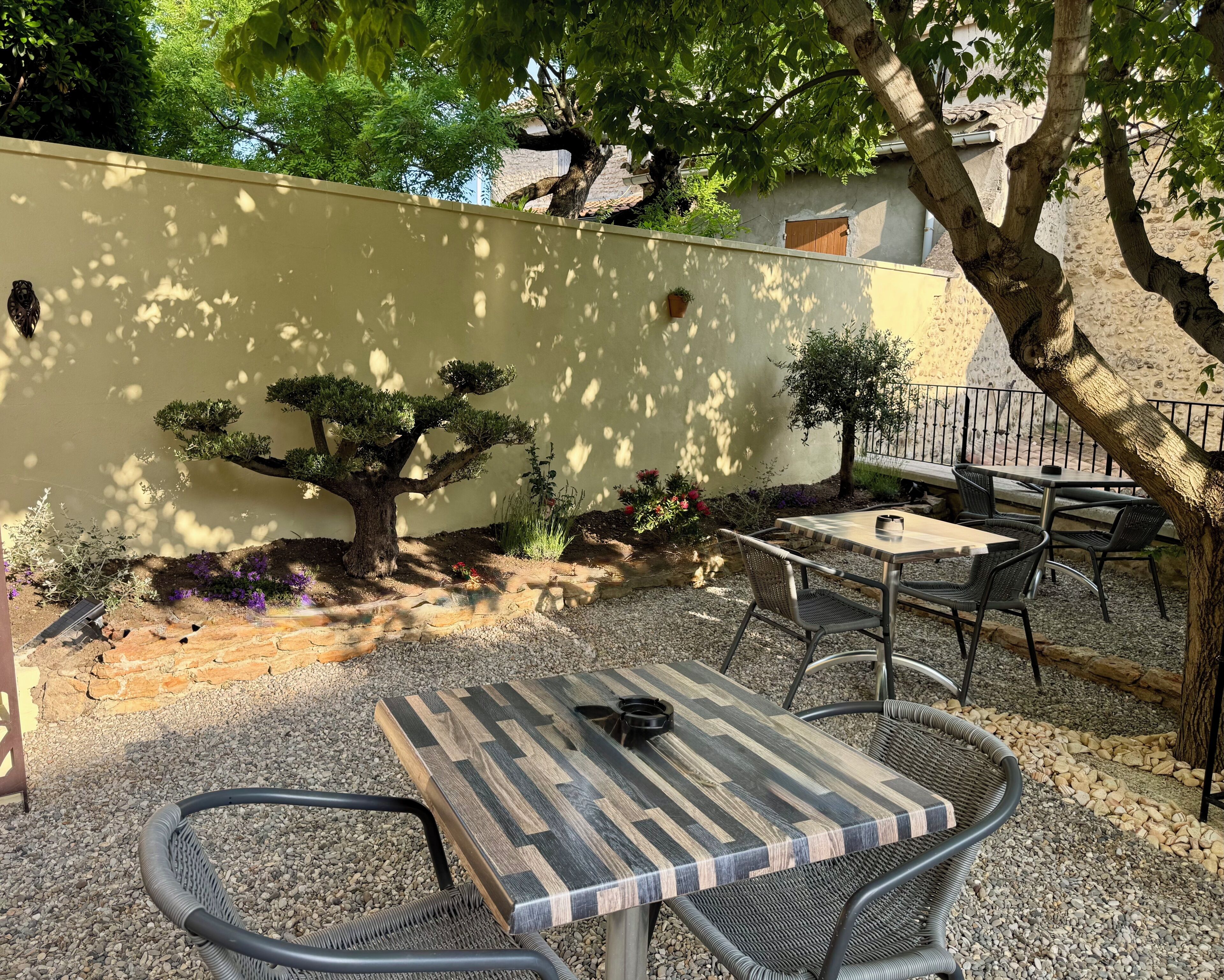 A patio with a table and chairs, surrounded by a low wall and trees.