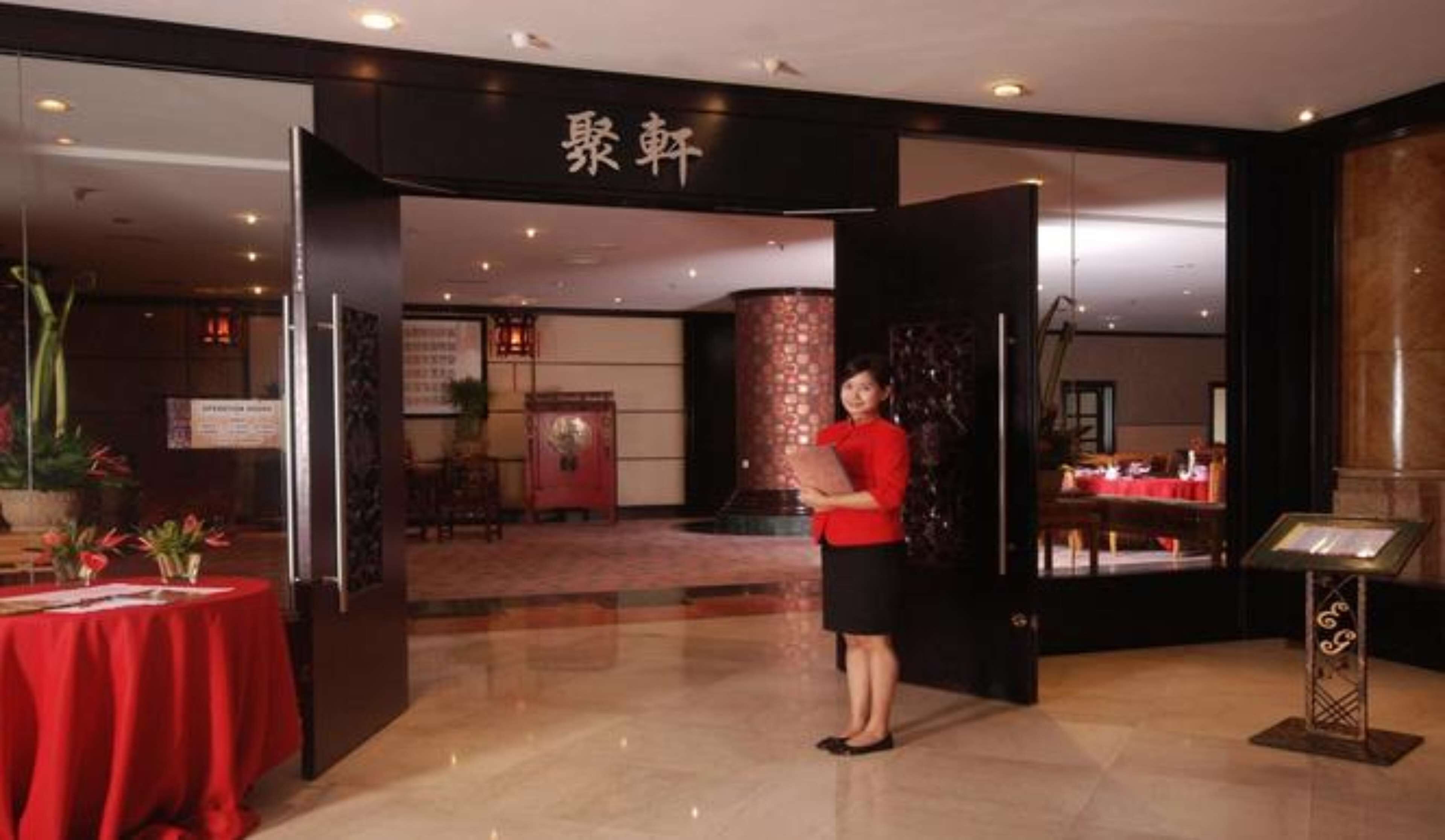 A hotel lobby with a reception desk, a red carpet, and a large pillar.
