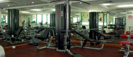 A gym with various exercise equipment, mirrors, and a red bench.