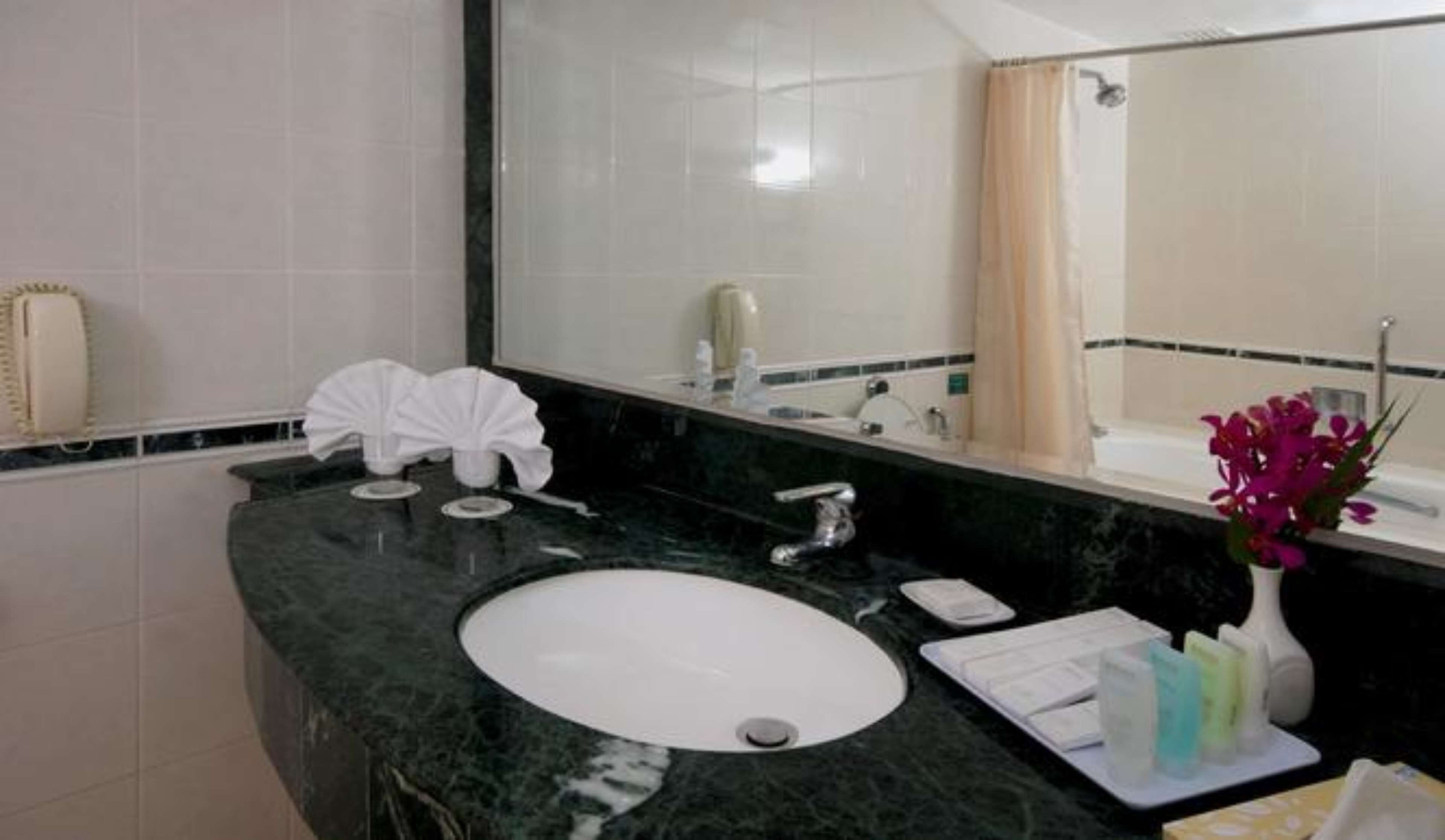 A bathroom with a marble sink, a large mirror, and a shower area.