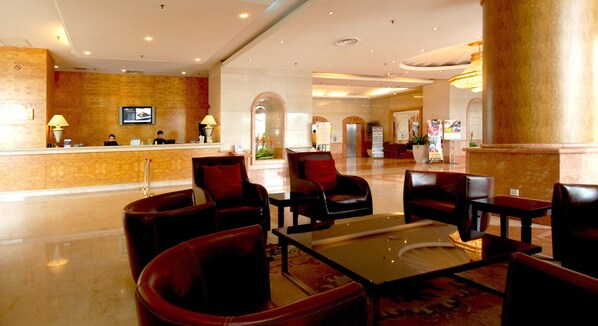 A spacious lobby with a reception desk, leather seating, and a polished floor.