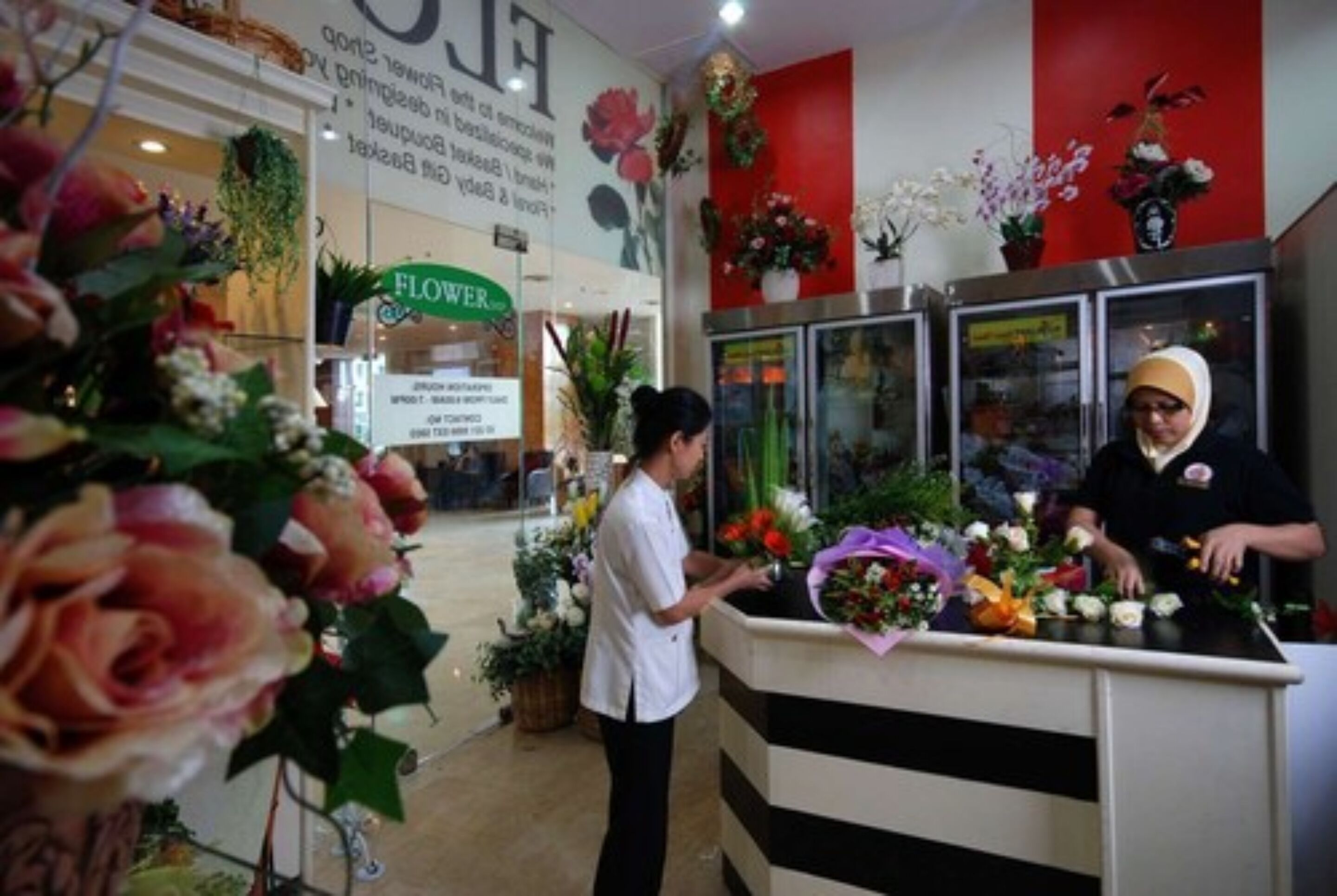 Interior de una floristería con un mostrador que exhibe diversas flores y plantas.