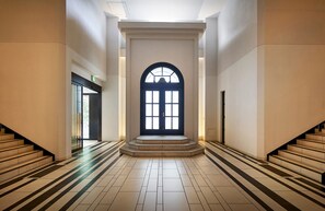 A spacious hallway with a large arched doorway, a staircase on the left, and a staircase on the right. - Daiwa Roynet Hotel Yokohama - Koen (Yokohama)
