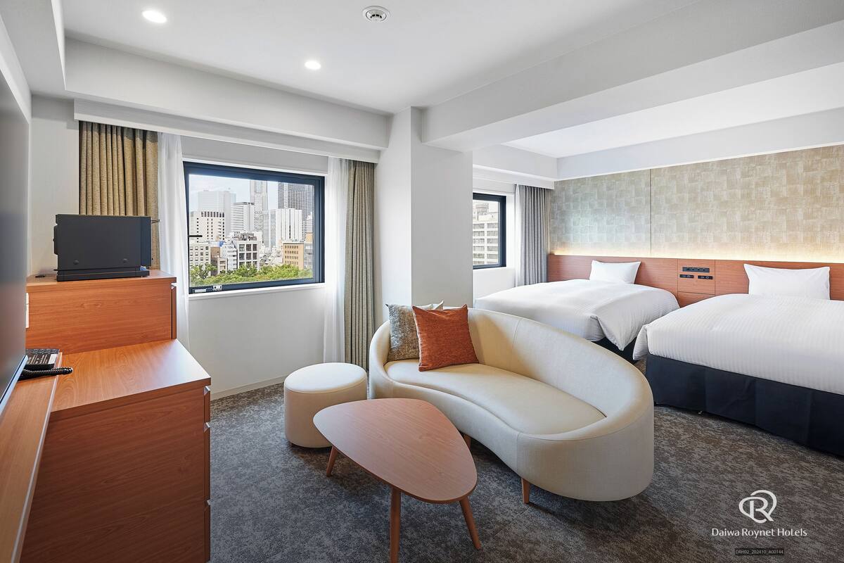 Une chambre d’hôtel avec un lit, un canapé, un bureau et une vue sur la ville.