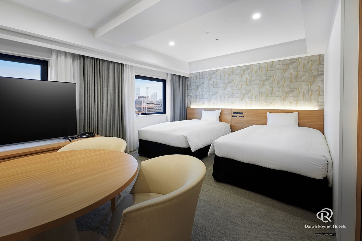 Une chambre d’hôtel avec deux lits, une télévision, un bureau et une vue sur la ville.