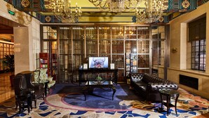 A luxurious lobby with a large chandelier, a television on a glass table, leather sofas, and a patterned carpet. - Jinjiang Metropolo Hotel Classiq, YMCA (Shanghai)