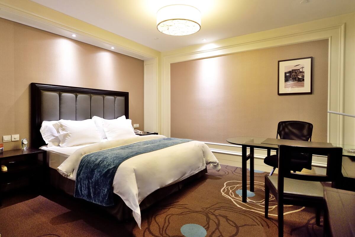 A hotel room with a large bed, a desk, and a chair.