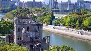 An urban landscape with a river, a large metal structure, and modern buildings in the background.