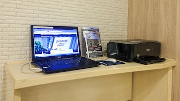 A laptop on a desk with a printer and a sign.
