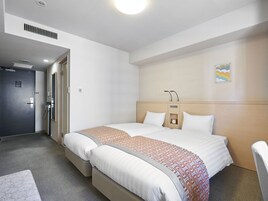 Habitación de hotel con una cama grande, una mesita de noche, un reloj en la pared y un pequeño estante.