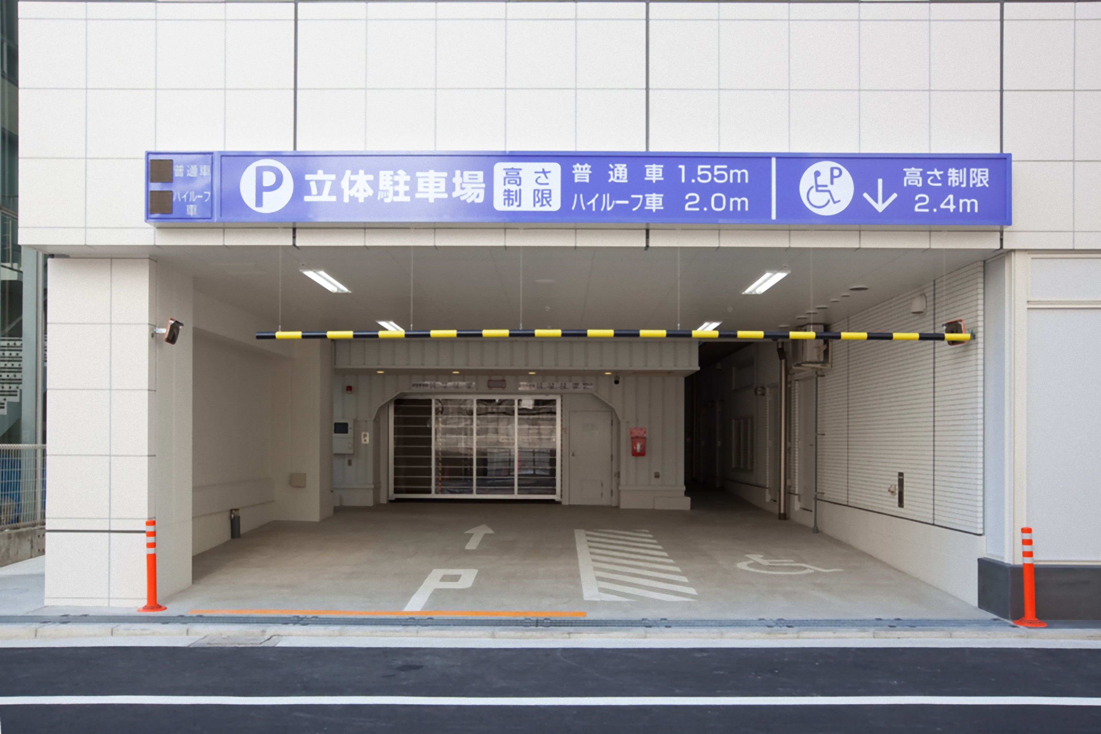 A parking garage entrance with directional signs and handicap accessibility symbols.