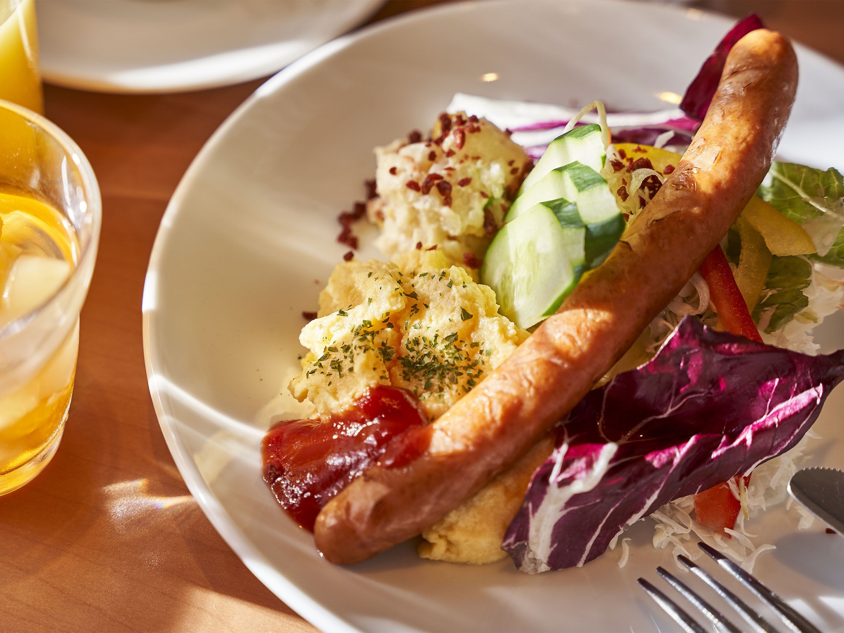 A plate of food with scrambled eggs, sausage, and vegetables.