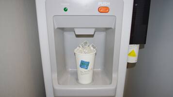 A water dispenser with a cup containing ice cubes.