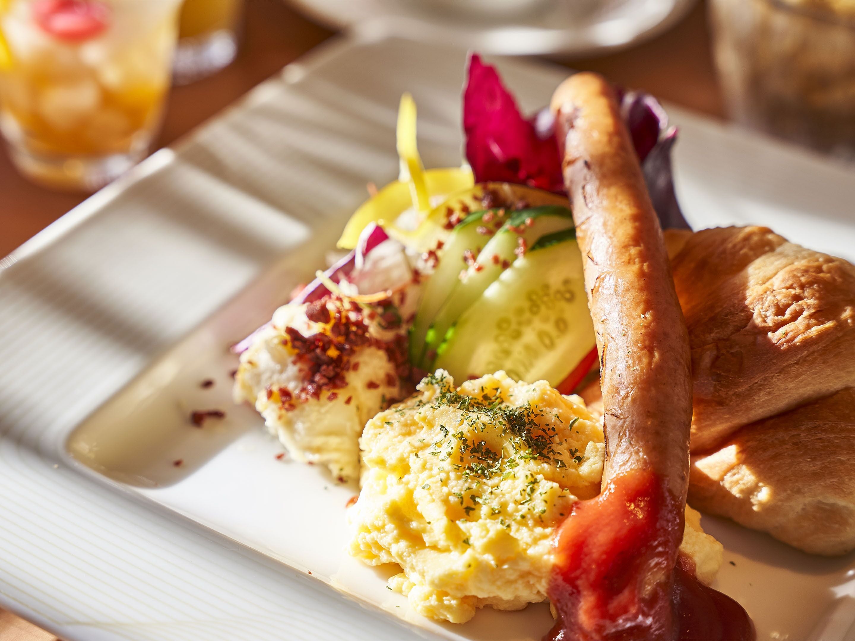 A plate of food with scrambled eggs, a sausage, and a side salad.
