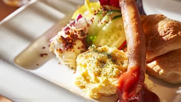 Une assiette contenant des œufs brouillés, une saucisse et une salade en accompagnement.