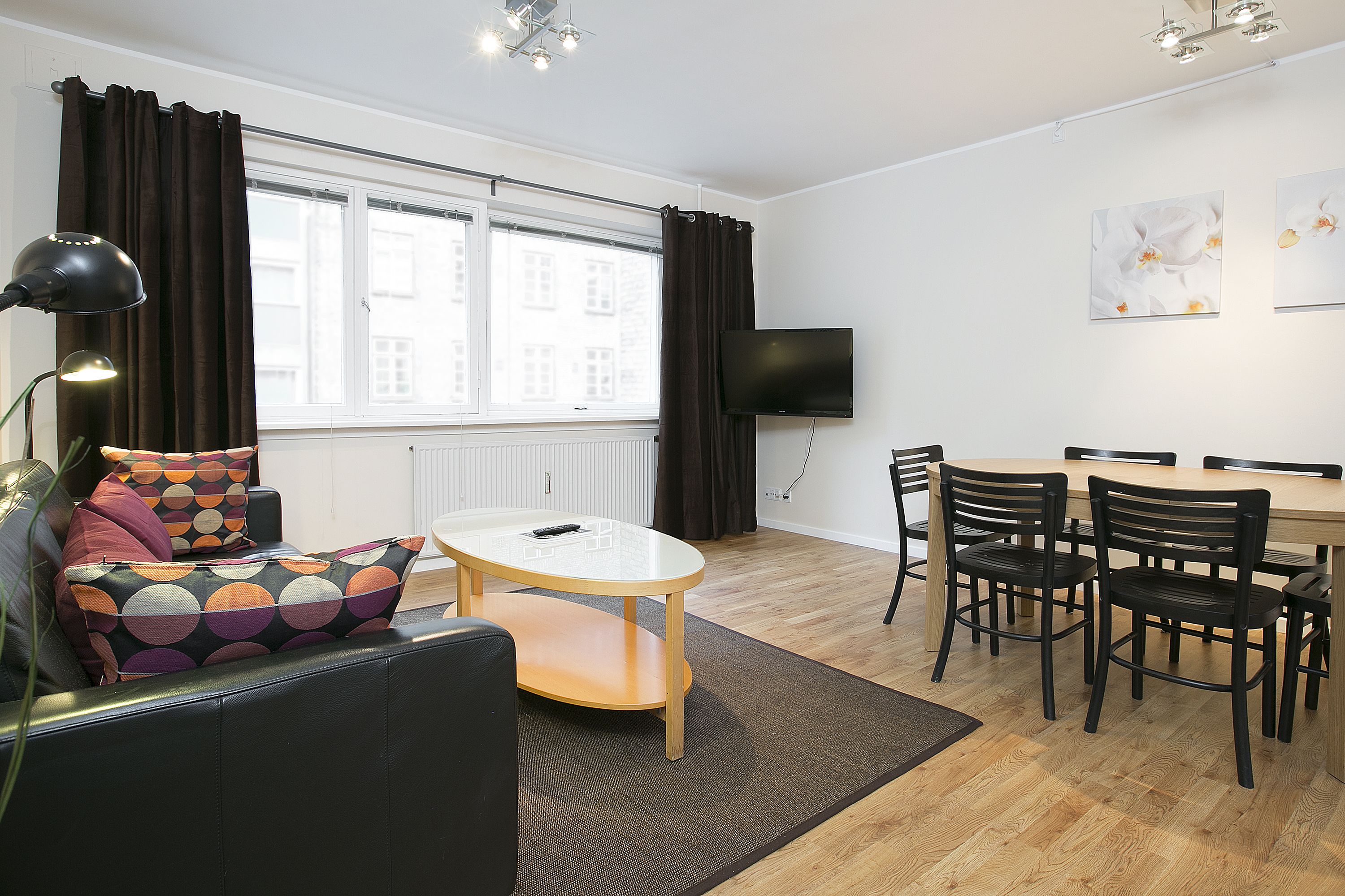 A modern living room with a sofa, a coffee table, and a dining area with chairs and a table.