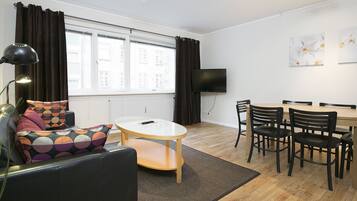 A modern living room with a sofa, a coffee table, and a dining area with chairs and a table.