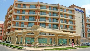 A multi-story hotel with a distinctive architectural design, featuring balconies and a central atrium. - Hotel Grenada - All Inclusive (Sunny Beach)