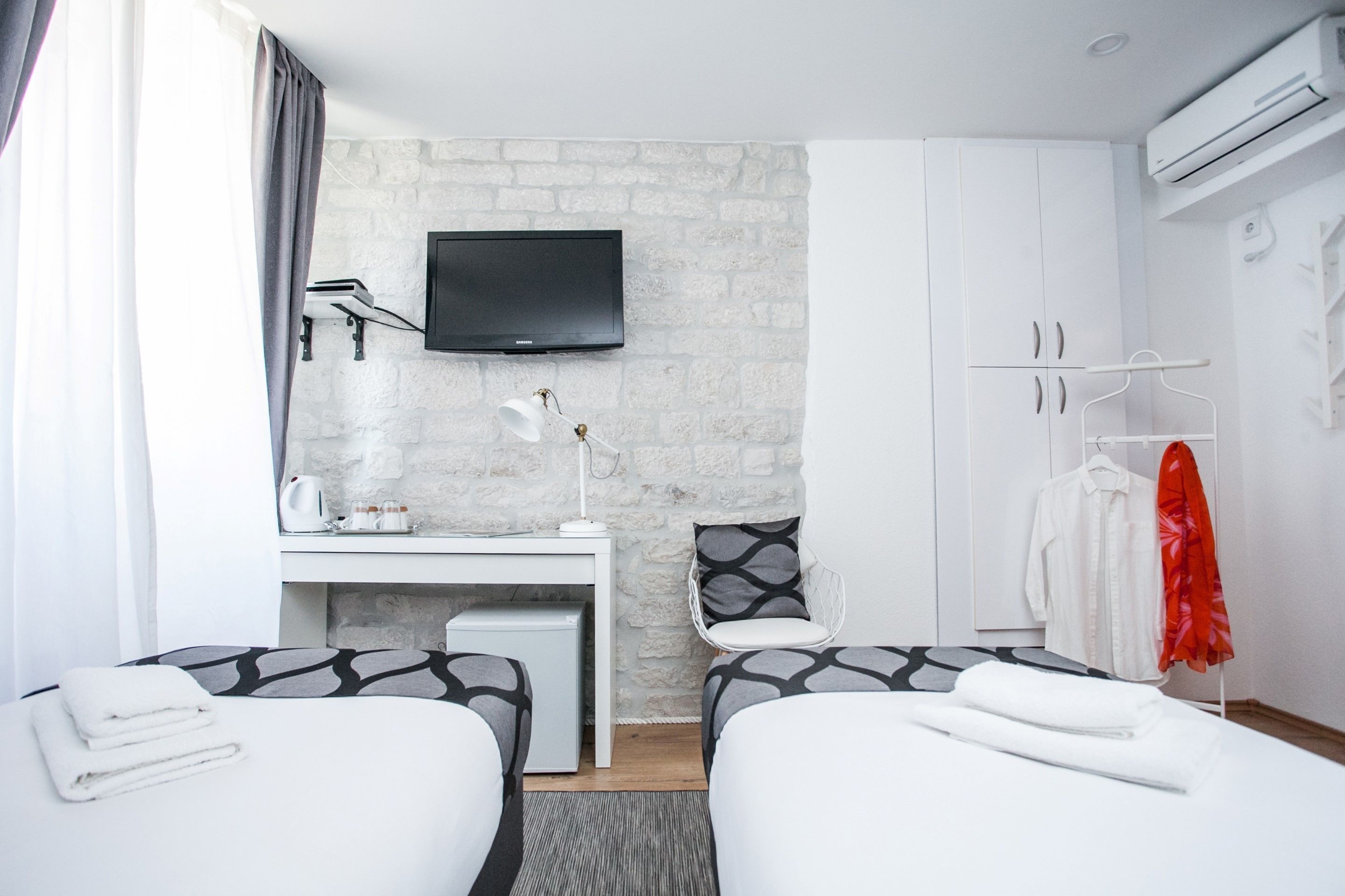 Una habitación de hotel con dos camas, un escritorio, un televisor y un armario.