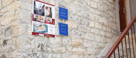 A stone building with a wooden staircase and two signs: one for 'Apartman' and another for 'Sobe'.