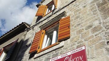 Un edificio de piedra con contraventanas de madera y un letrero que dice 'Pizzeria Obrov'.