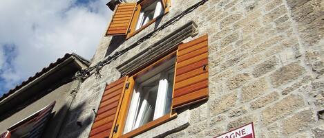 Un bâtiment en pierre avec des volets en bois et une enseigne indiquant « Pizzeria Obrov ».