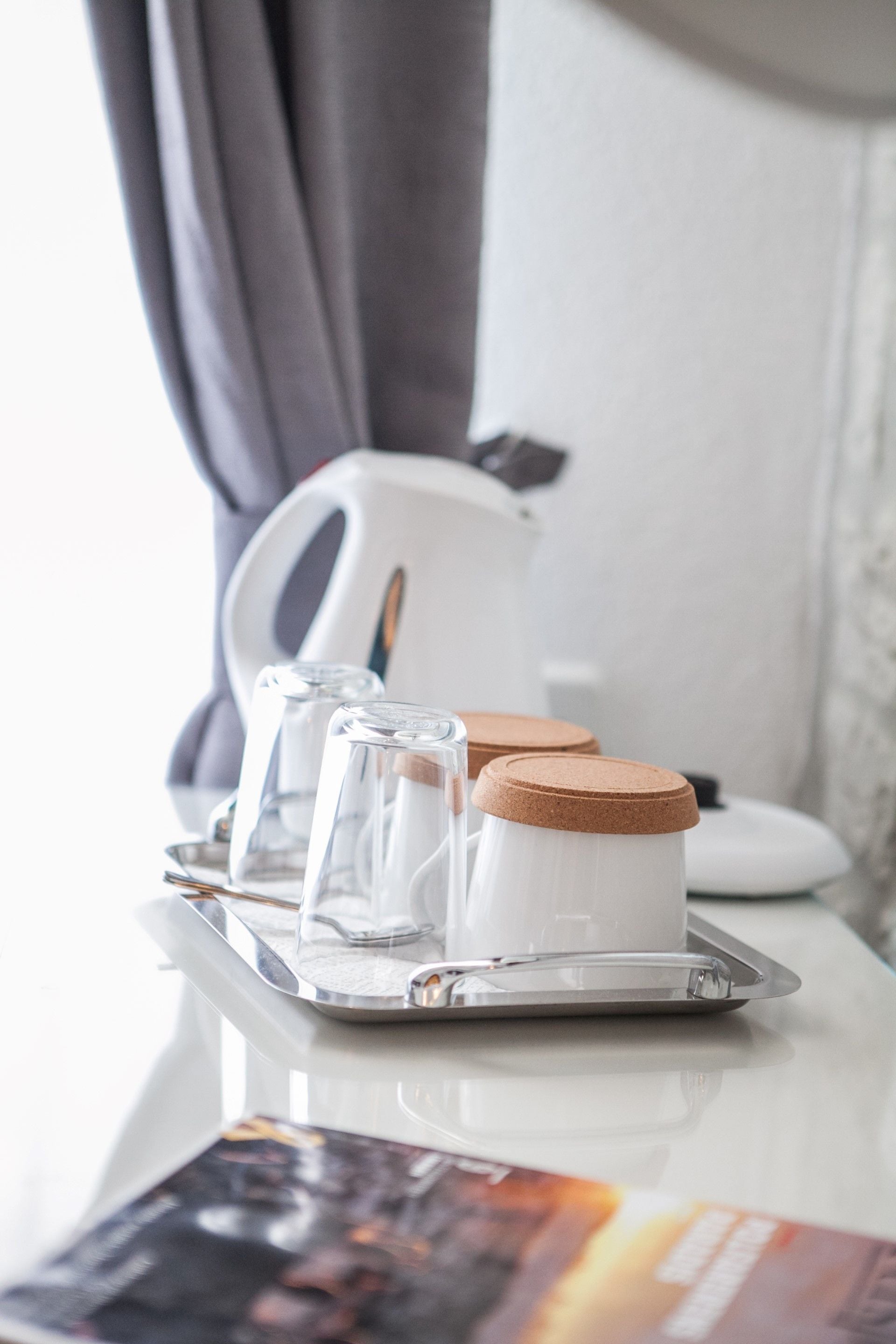 A tray with two glass containers and a white mug on a white table.