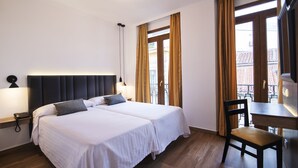 A hotel room with two beds, a desk, and a chair. - Hotel Madrisol (Madrid)