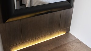 A modern bedroom with a large mirror, a bedside table, and a built-in bench with integrated lighting. - Hotel Madrisol (Madrid)