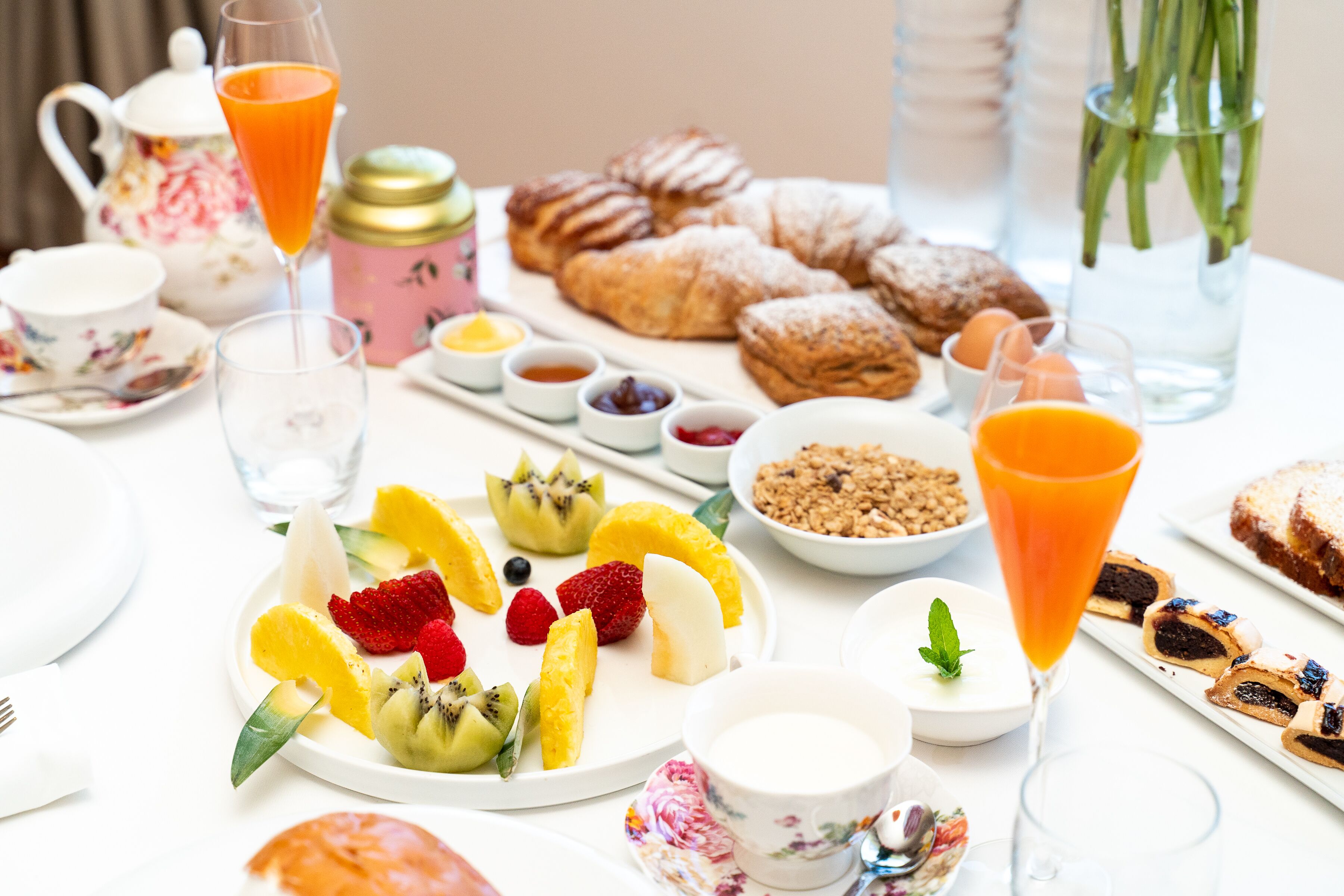 A breakfast setting with various pastries, fruits, and beverages on a table.