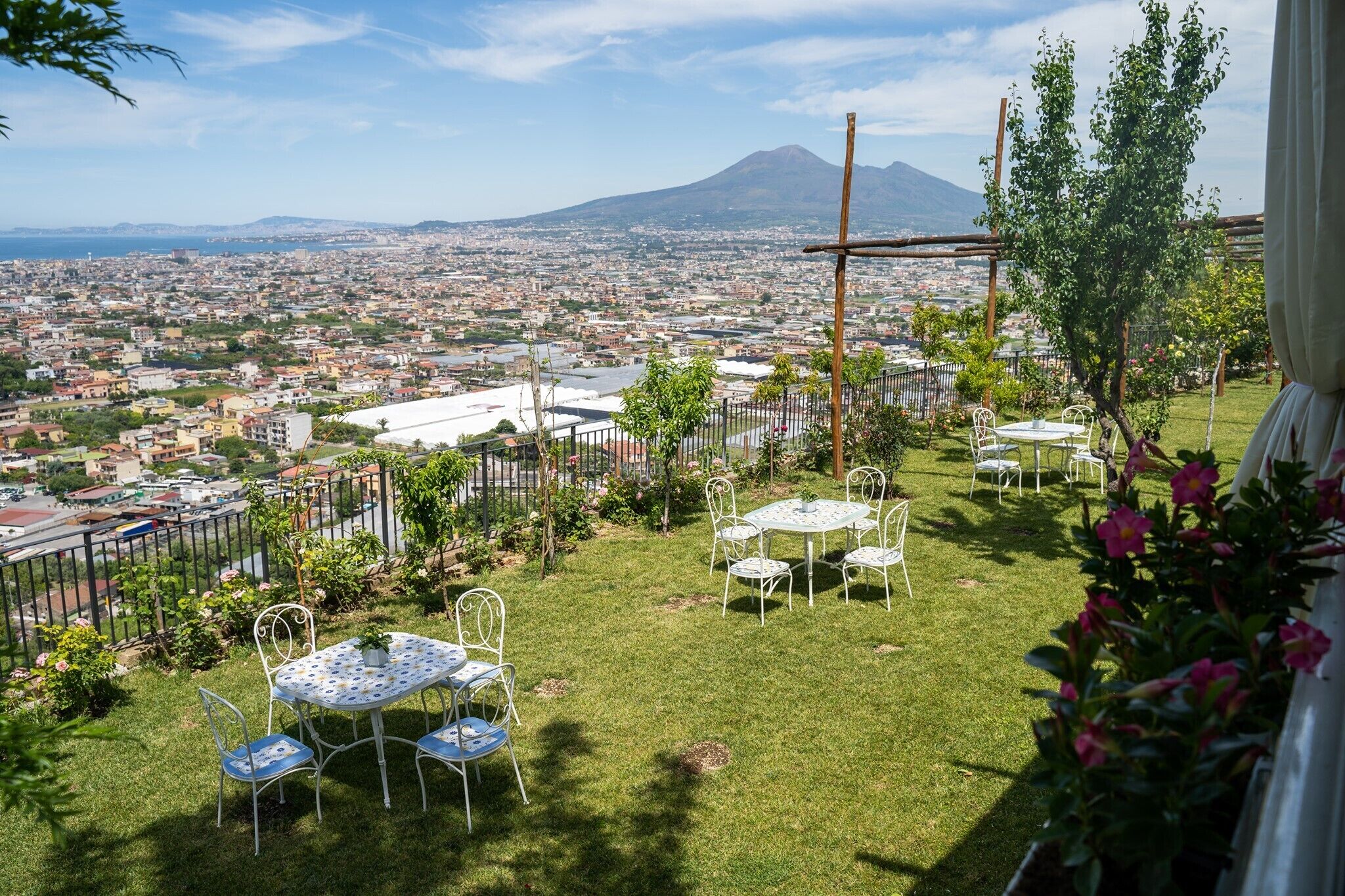 Una terraza con mesa y sillas, vista a un paisaje urbano y una montaña al fondo.