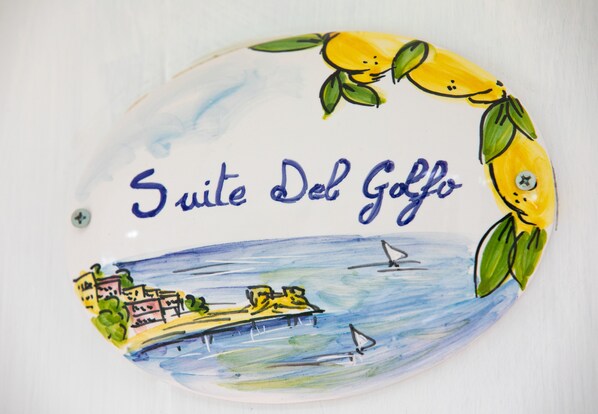 A ceramic sign with 'Suite Del Goffo' text and a maritime scene with buildings and boats.