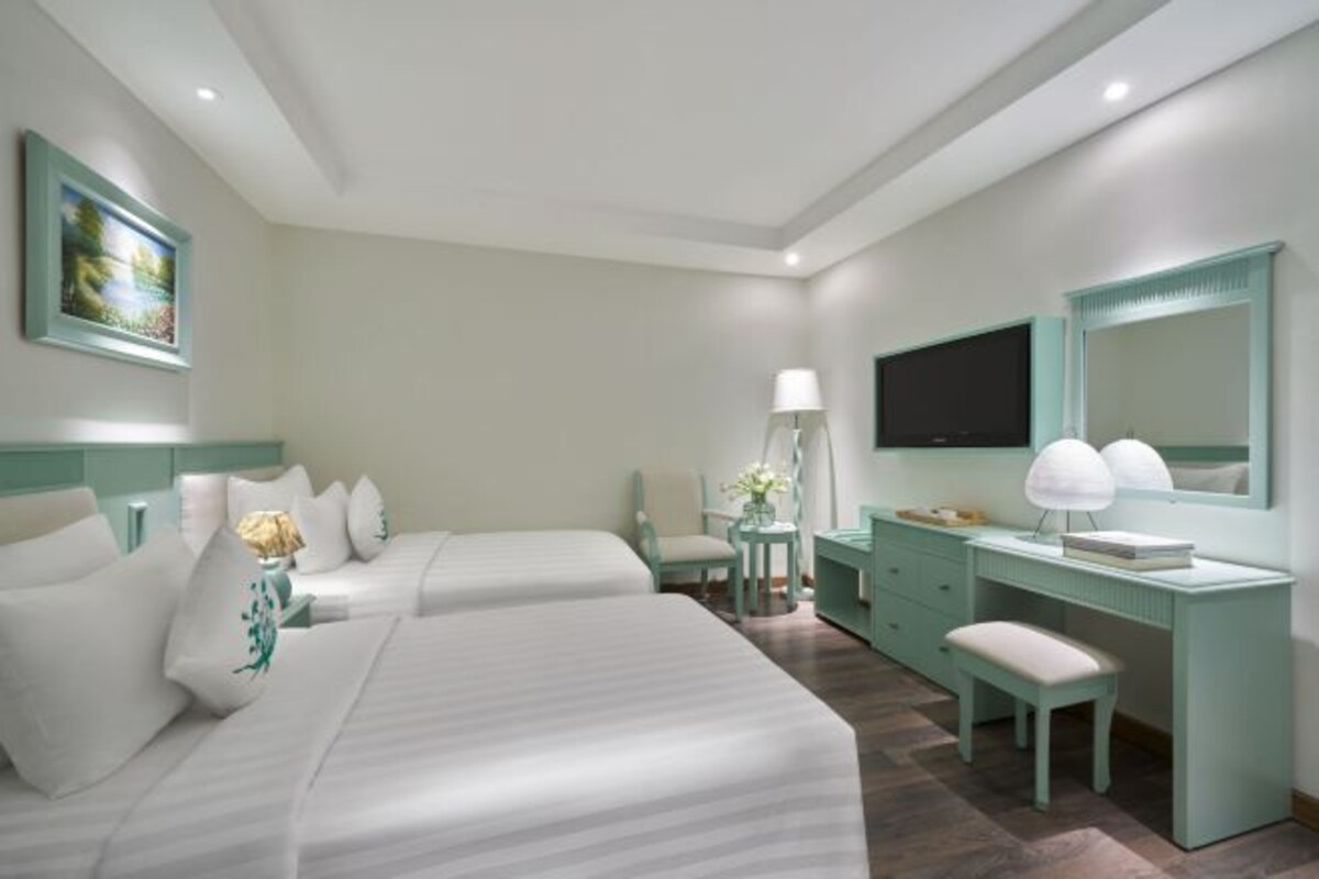 Een hotelkamer met twee bedden, een bureau, een stoel, een televisie en een spiegel.