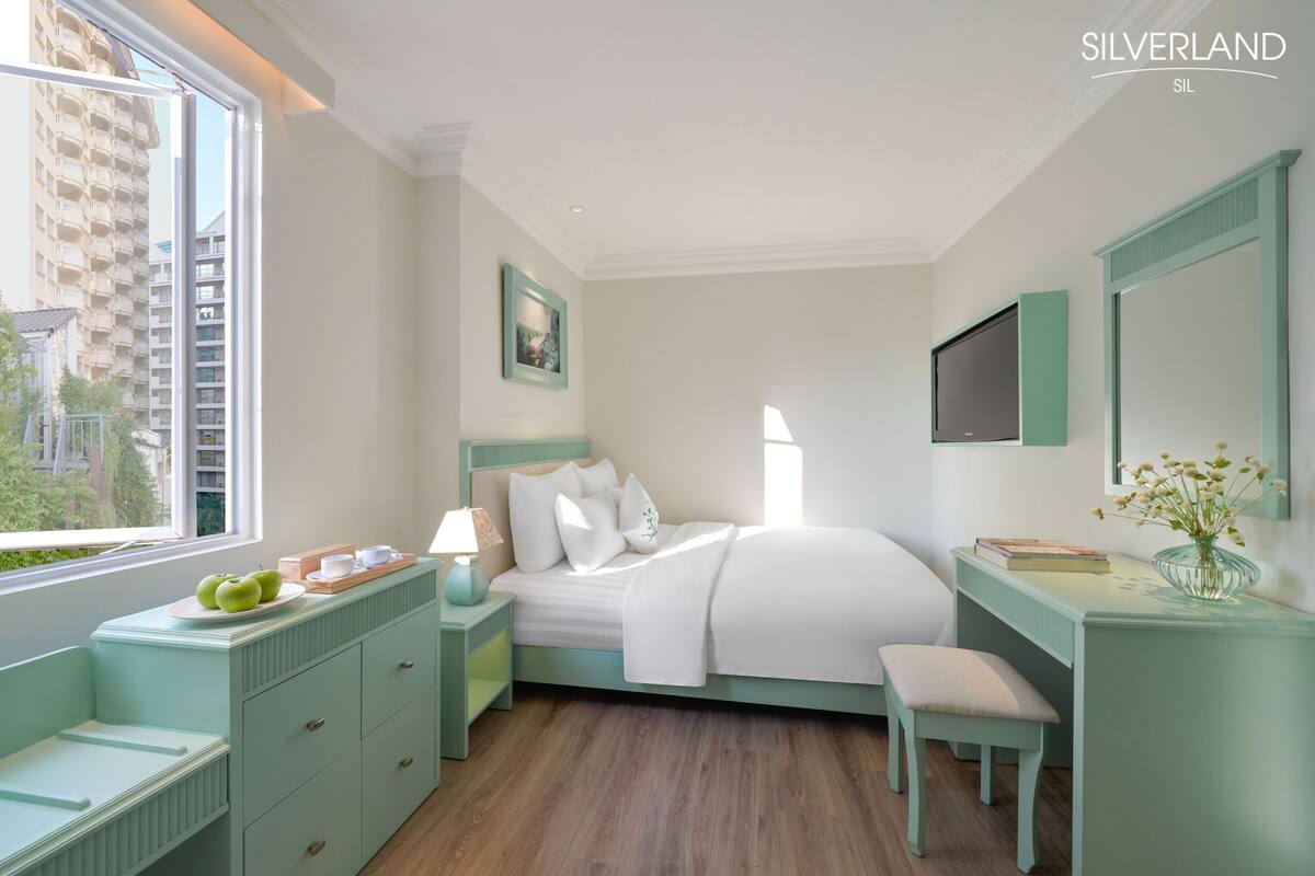 Un dormitorio con cama, mesita de noche y escritorio con silla.