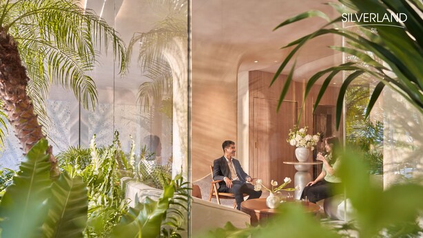 Un intérieur moderne avec un mur de verre, une végétation luxuriante et un espace détente comprenant une table et des chaises.