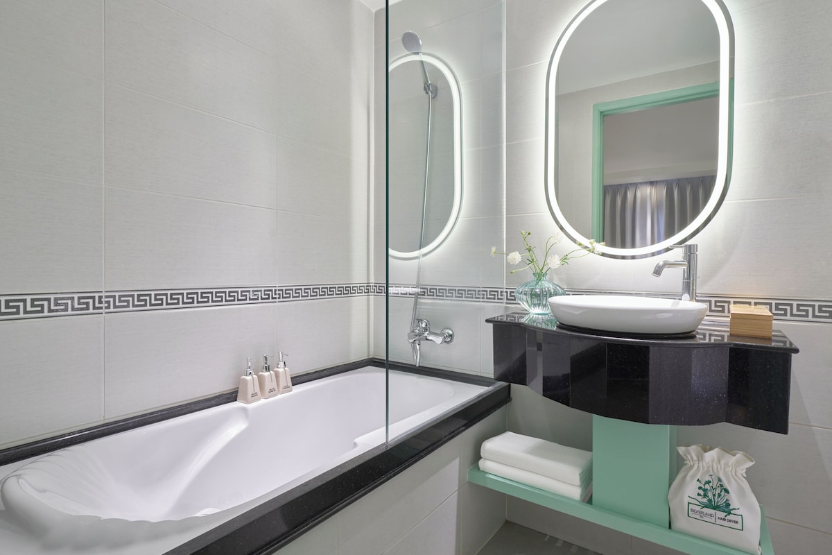 A modern bathroom with a bathtub, a vanity with a sink, and a large mirror.