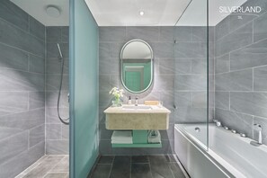 A modern bathroom with grey tiles, a white bathtub, a beige sink, and a glass shower enclosure. - Silverland Sil Hotel (Ho Chi Minh City)